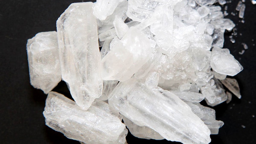 Light-coloured crystals – the drug ice – on a dark table.