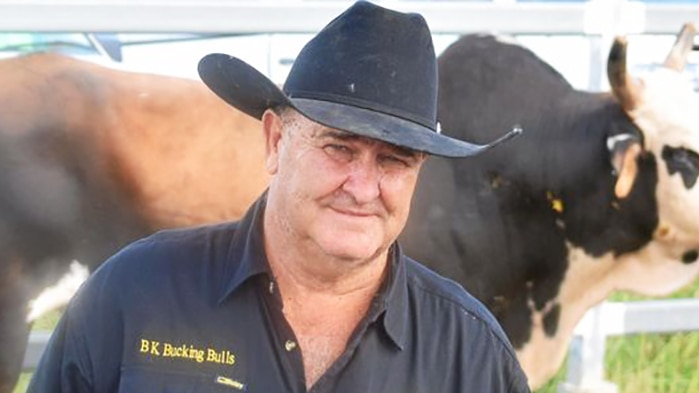 Brian King standing in front of a large bull in a pen