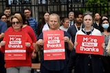 Three women hold signs that read: "More than thanks"