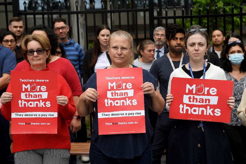 Three women hold signs that read: "More than thanks"