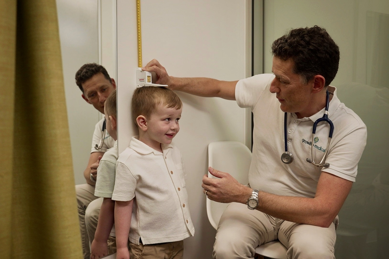 A doctor measuring the height of a three-year-old boy.