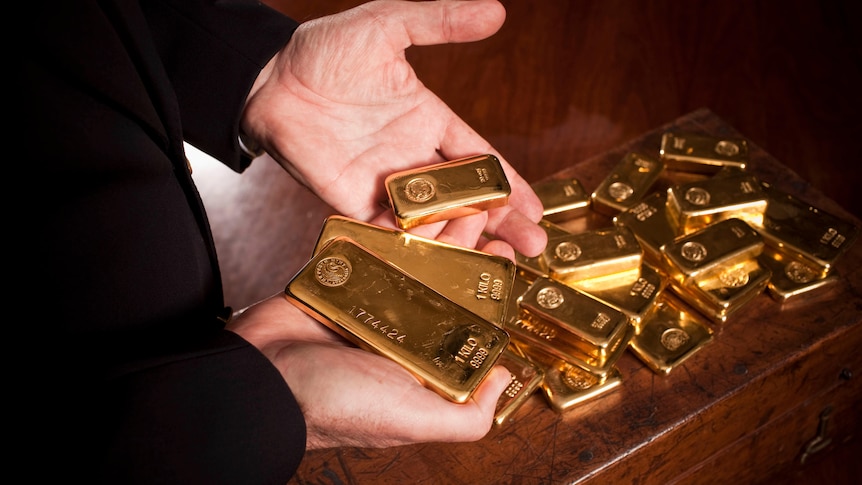 A man's hands holding gold bars. 