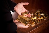 A man's hands holding gold bars. 
