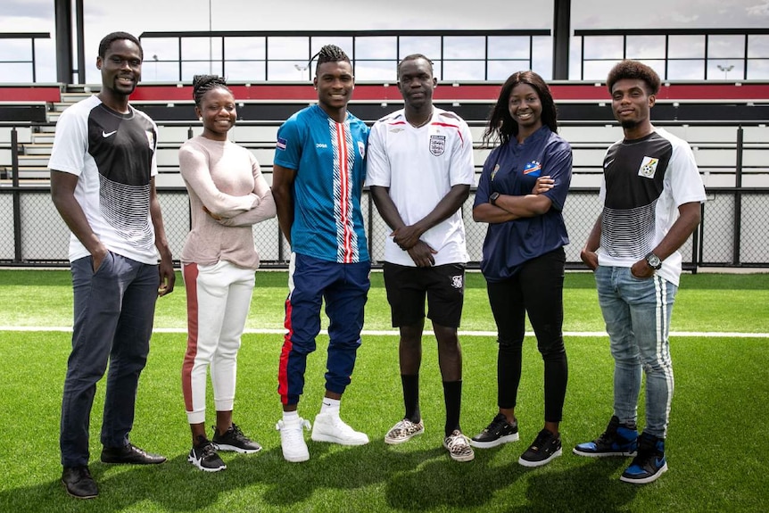 Men and women stand on a football pitch