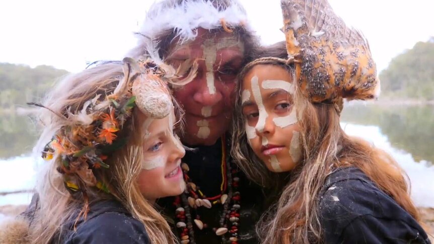 Two girls with their grandmother all with ochre face painting