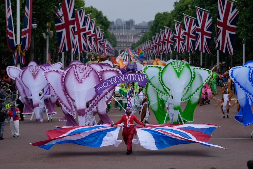 People parade in brightly colored costumes during the Platinum Jubilee Choice in front of Buckingham Palace in London.