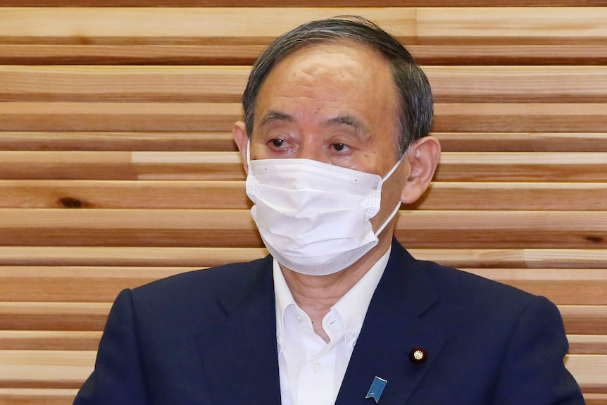 Japanese PM Yoshihide Suga addresses a press conference in Tokyo wearing a mask, where he announces his intention to step down.