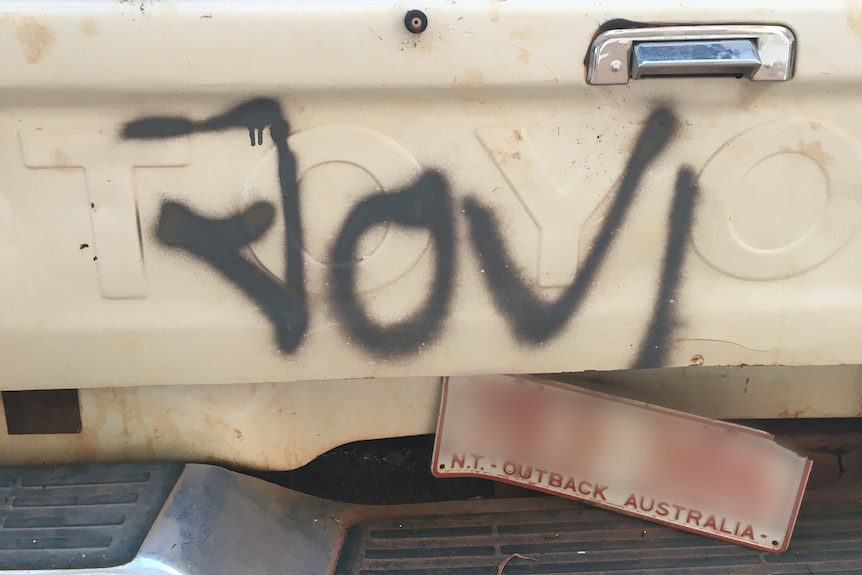 The back of a white ute, with the word "Jovi" graffitied on the back in black spraypaint.