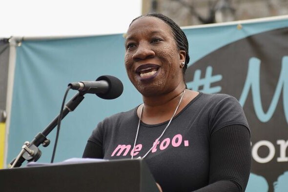 Tarana Burke, an African American woman speaking at a rally while wearing a tshirt that says 'me too.'
