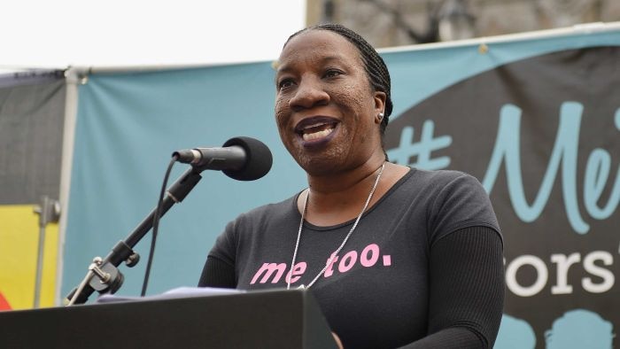 Tarana Burke, an African American woman speaking at a rally while wearing a tshirt that says 'me too.'