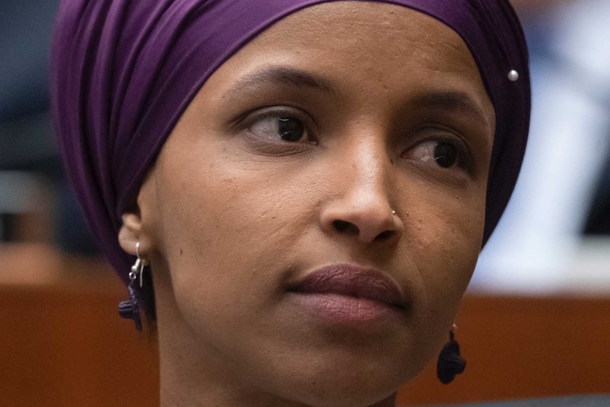 Minnesota Democrat Ilhan Omar wears a purple headscarf and her head is turned towards the left