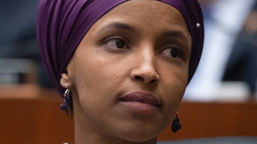 Minnesota Democrat Ilhan Omar wears a purple headscarf and her head is turned towards the left