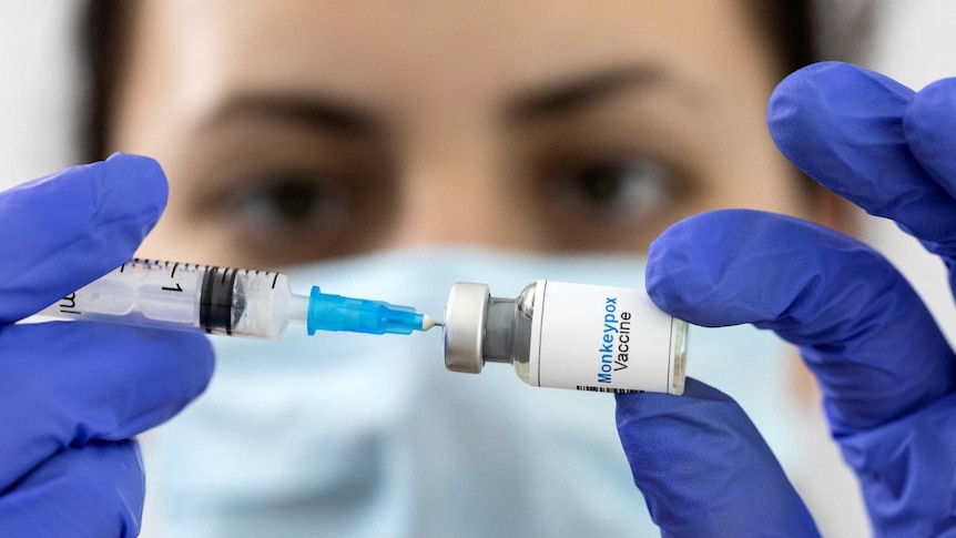 A woman holds a mock-up vial labeled "Monkeypox vaccine"