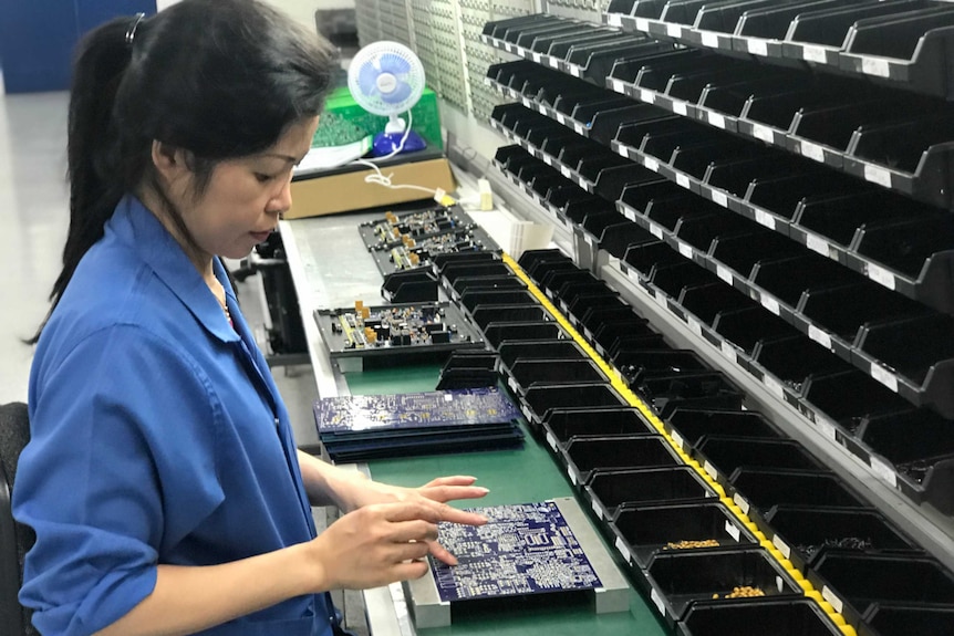 A woman builds electronics equipment.