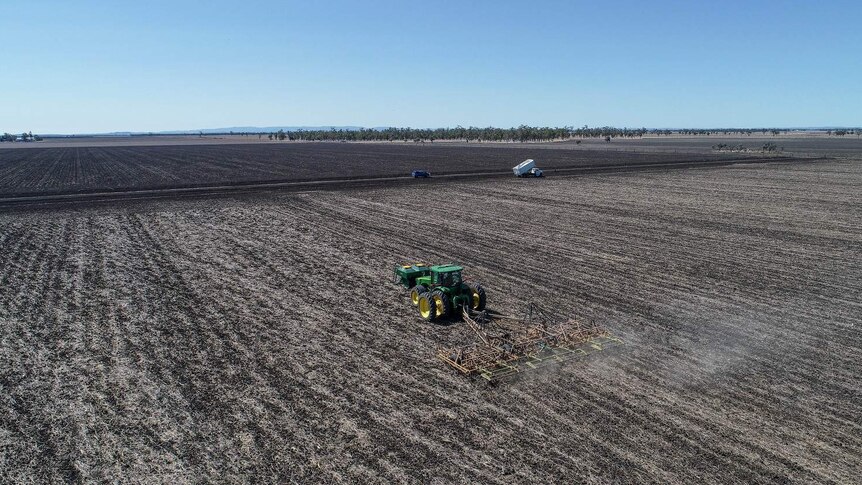 Drone shot of tractor in crops on dry grain farm