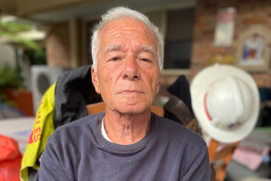 A man with grey hair with a fireman's hat behind him