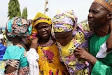 A released Chibok girl embraces her parents, her mother's face is covered in tears. They are all brightly dressed.