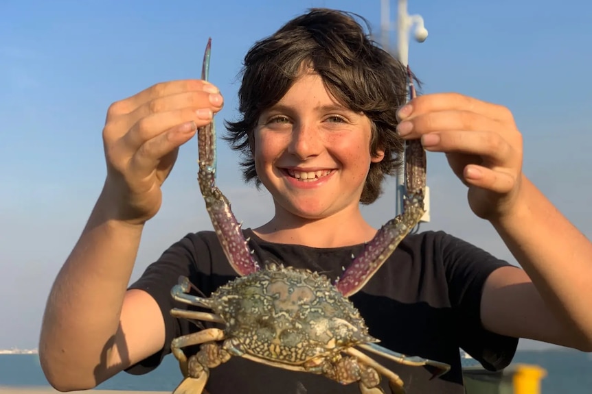 A child holding up a crab for the camera