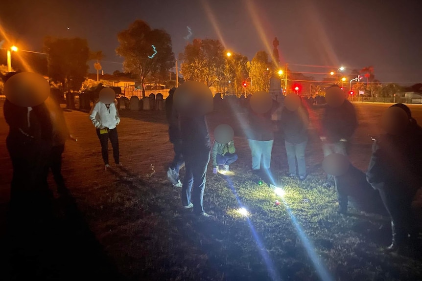 People at a ghost tour at the Ipswich cemetery at night.