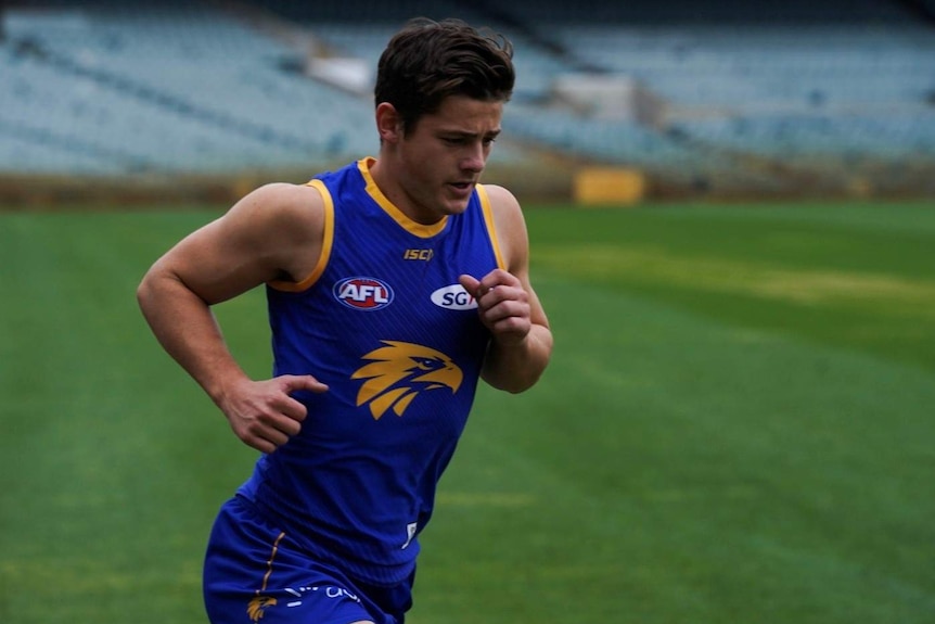 Hamish jogs on the field. The background is out of focus.