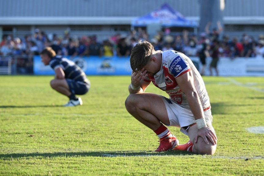 A St George Illawarra Dragons NRL player kneels as he reflects on his side's loss to the Cowboys.
