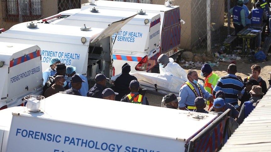Paramedics load one of the victims, in a body bag, into a waiting pathology services van.