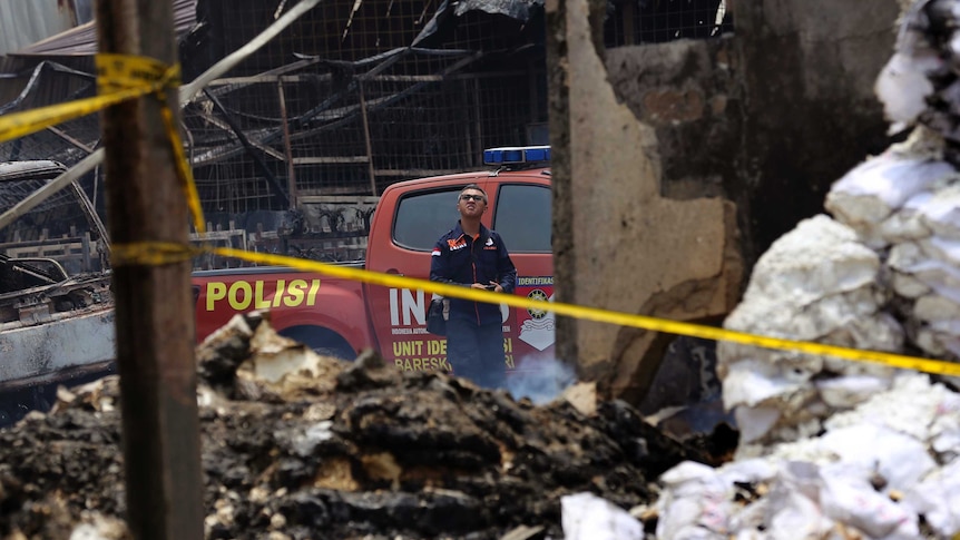 A police investigator inspects the site of an explosion and fire at a fireworks factory in Tangerang