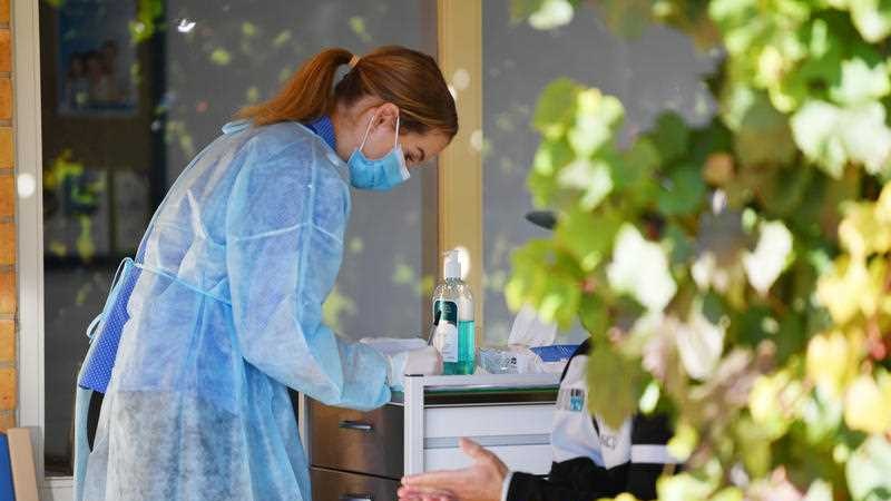 A nurse in a mask treating a patient.