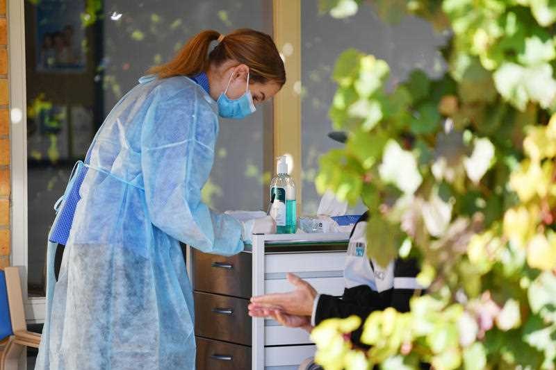 A nurse in a mask treating a patient.