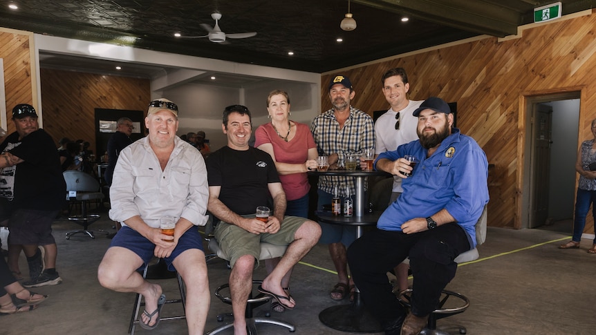 A group of people sitting around a bar table holding drinks.