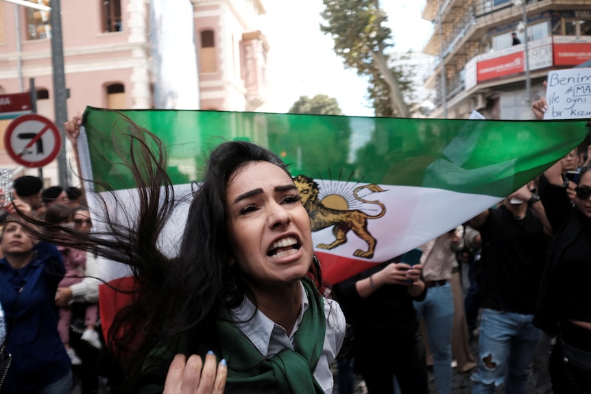 A woman with flowing black hair shouts shouts at a protest