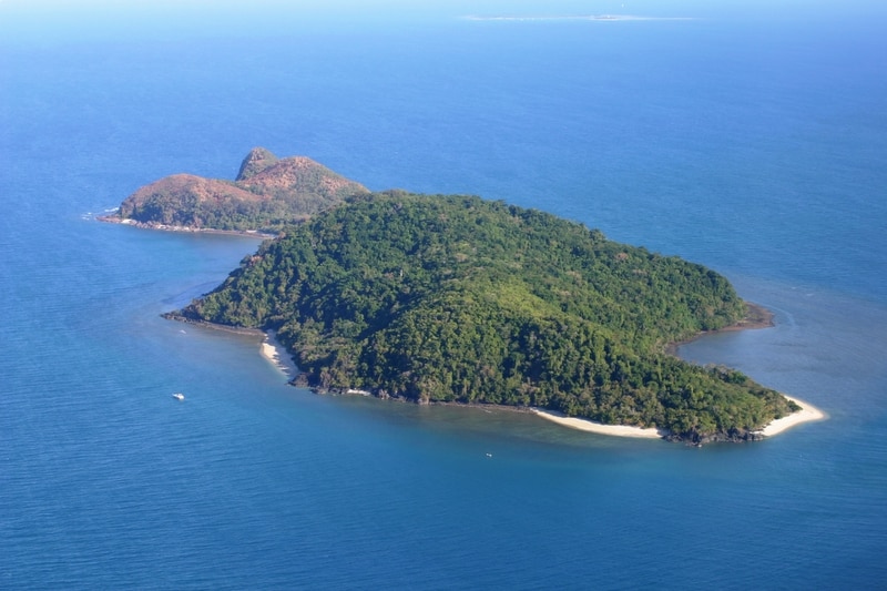 Aerial photo of a rainforested, hilly island surrounded by ocean.