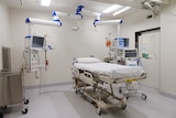 A white room filled with an ICU bed, several monitors and other medical equipment