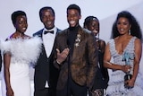 Five cast members from Black Panther stand on stage in ball gowns and suits to accept SAG award.