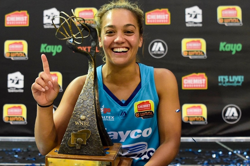 Leilani Mitchell smiles as she sits with her MVP trophy and holds a finger up to gesture number one.