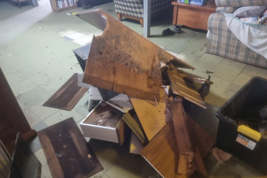A pile of broken furniture on a flooded floor.