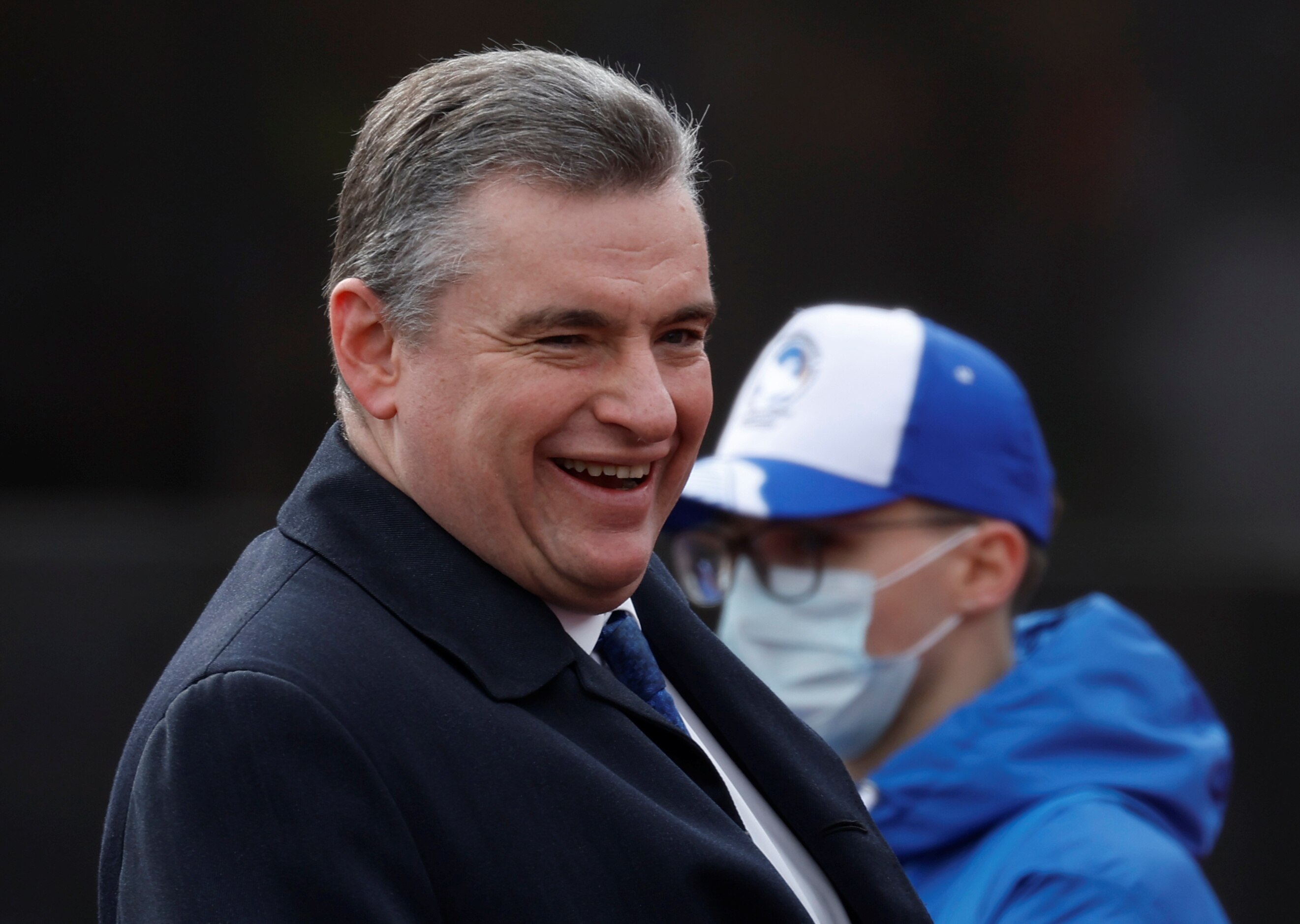 A man in a suit laughs as he stands outside