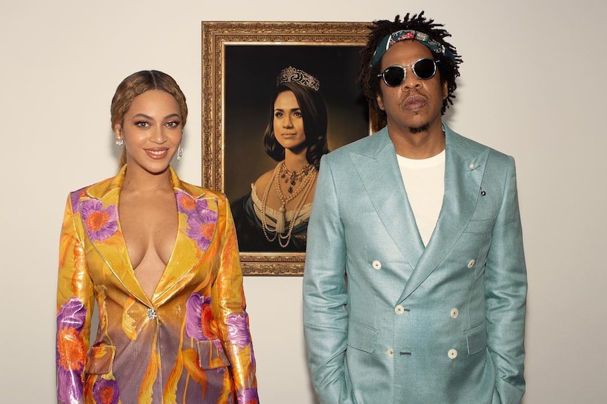 Beyonce and Jay Z stand in front of a portrait of Meghan Markle