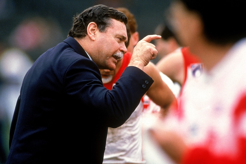 Ron Barassi points while wearing a suit