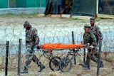 A detainee at Camp X-Ray is carried after being interrogated by officials
