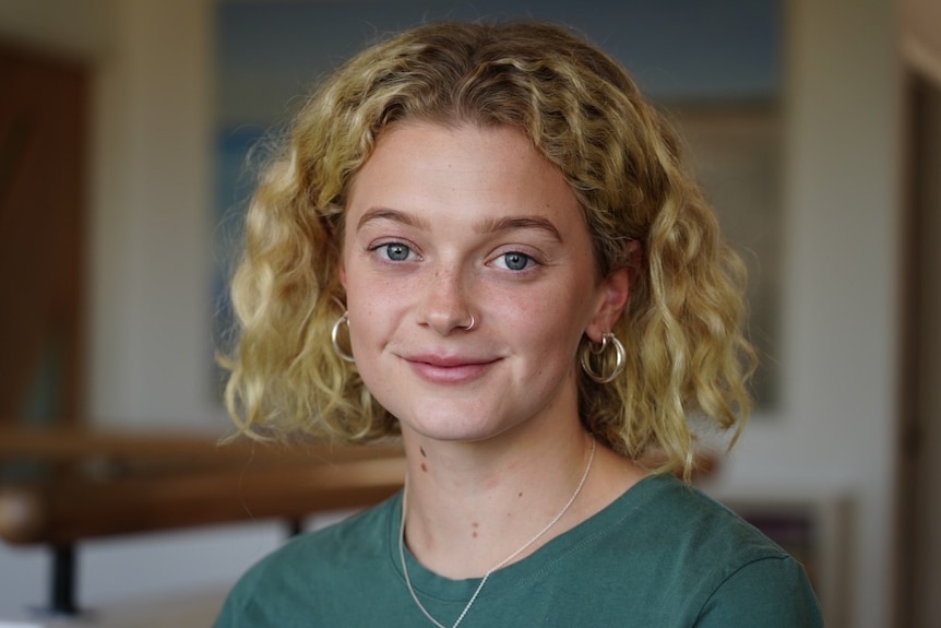 A young woman with a green shirt and blonde hair poses for a photo