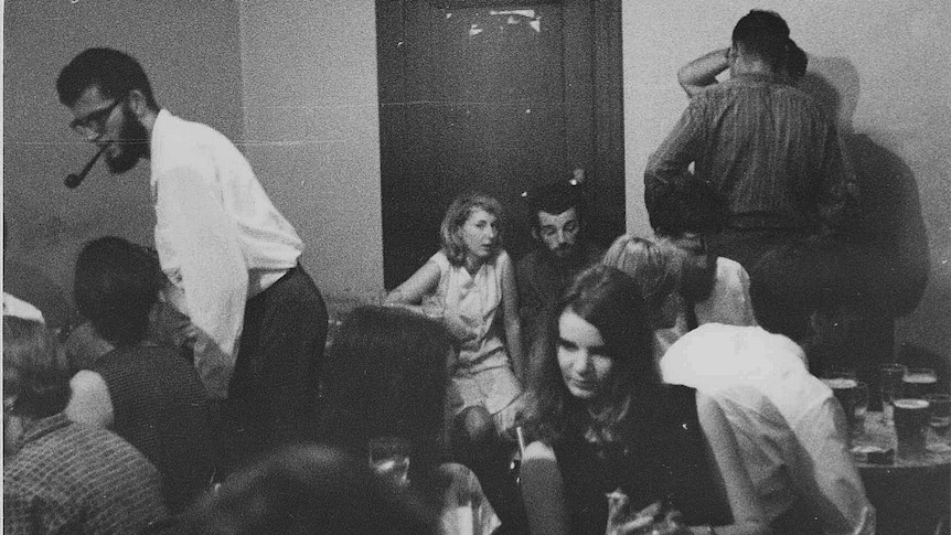 B&W photo of people sitting around chatting in a pub