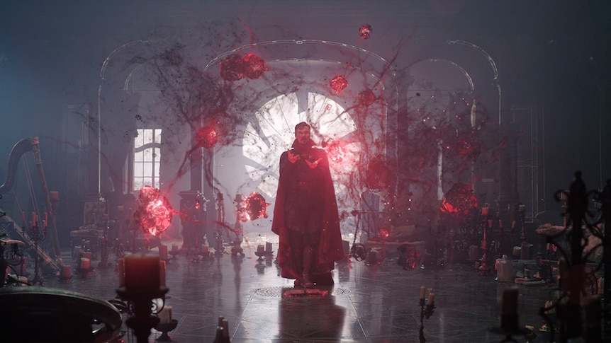 A sorcerer is surrounded by glowing red shapes in a still from a movie.