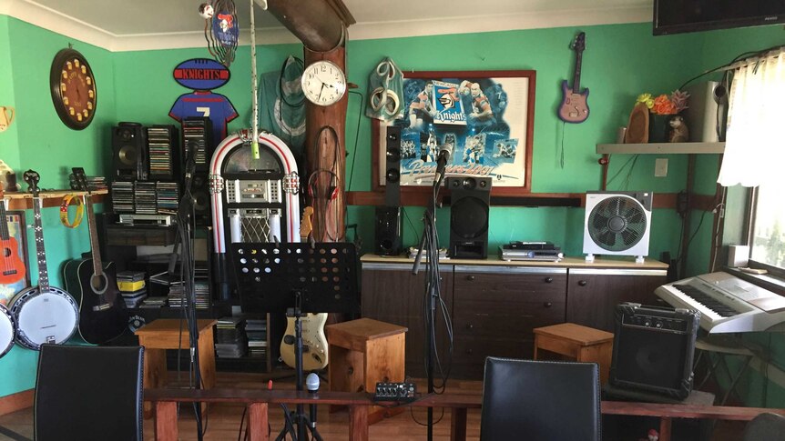 A small wooden stage set up inside the Warrell Creek Tavern with microphones and a jukebox.