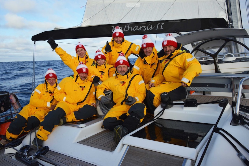 Crew of yacht pose for photo on deck.