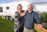 Man and woman standing in front of caravan