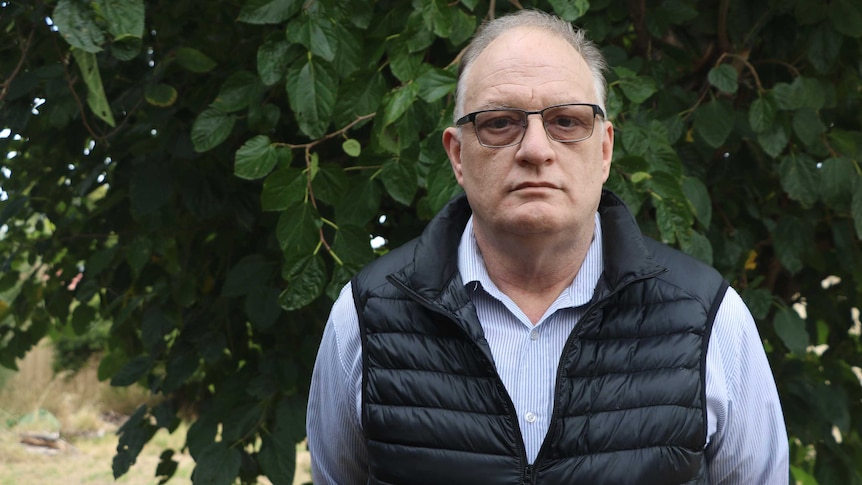 Mr Schutt stands in front of a green background.