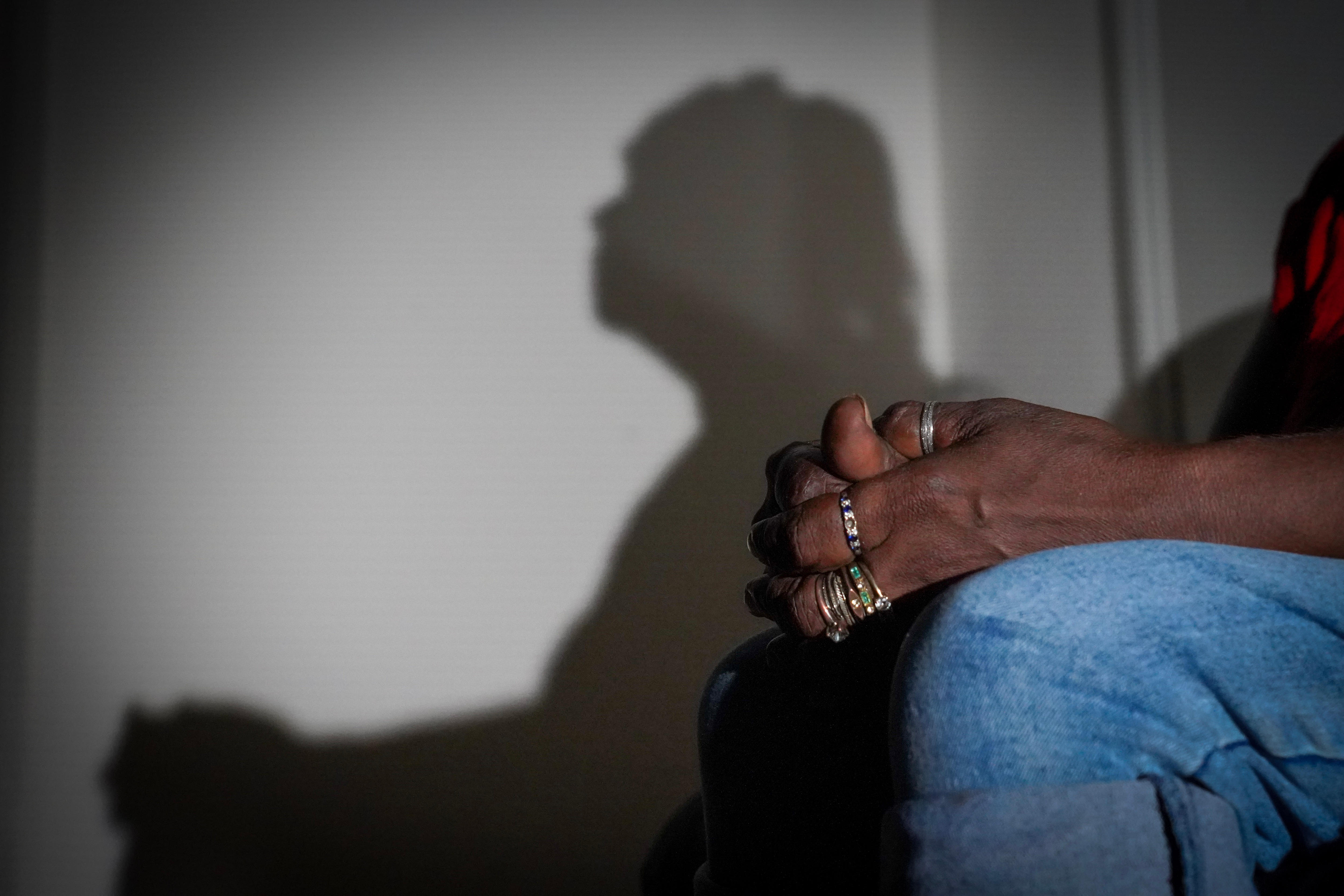 Mãos de mulher de joelhos com sombra na parede. 