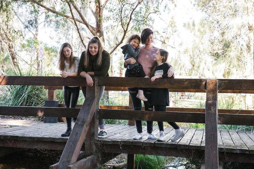 Christielee Plumridge stands on a low bridge with her four daughters in Camden depicting the responsibility of parenting.