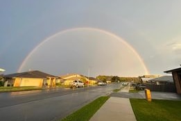 a rainbow over a sodden suburban street